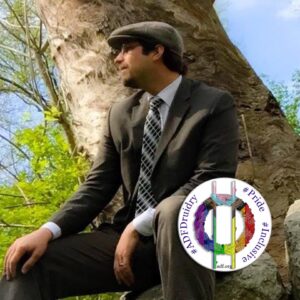 Rev. Dangler sitting beside a tree with an ADF Druidry profile badge in lower right