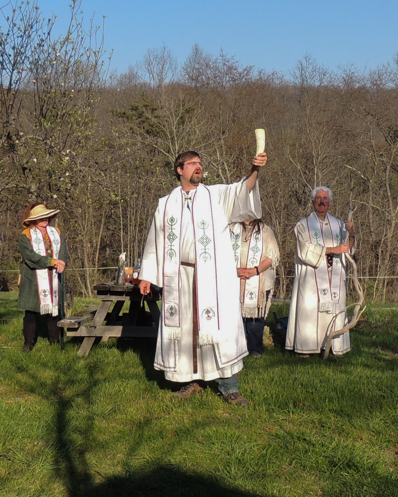 Rev. Dangler lifts a horn to the sky while other ADF Priests look on