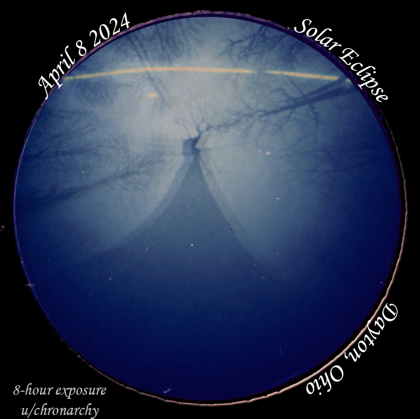 Rounded photo of trees and the path of the sun, broken where the eclipse occurs