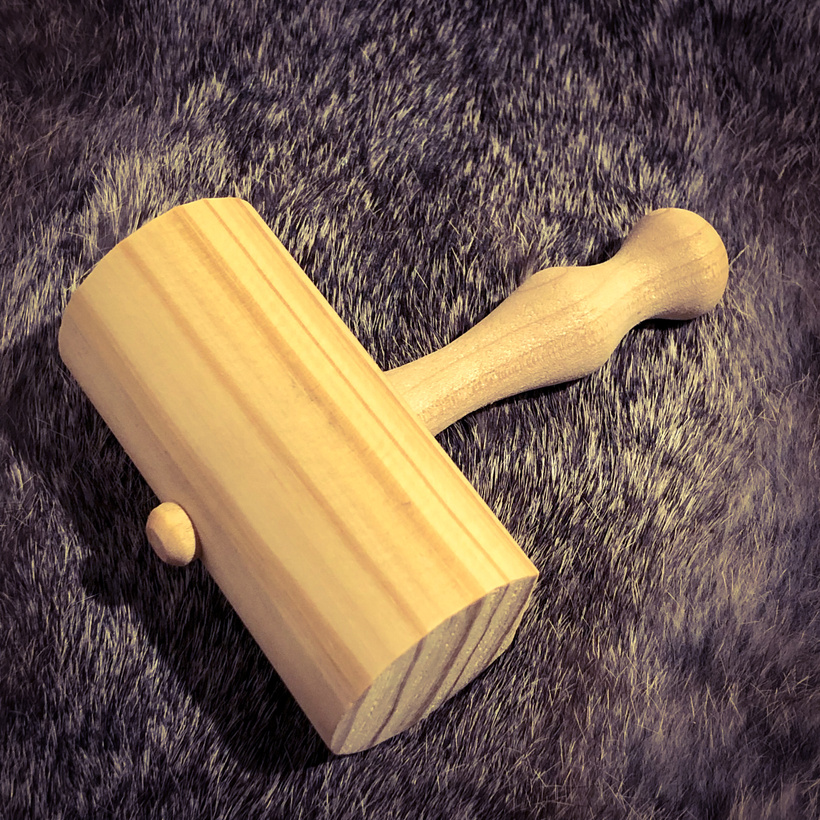 A small wooden hammer made of two pegs and a railing cut to size