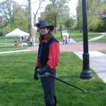 MJD in a swashbuckler outfit, long hair and a sword, on a field of grass