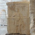 A bearded man in a short tunic over one shoulder, with tongs in his left hand by his side and a hammer in his right held mid-torso. VOLCANUS inscribed above.