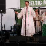 MJD on a stage in ritual whites, speaking at a microphone