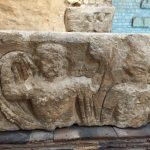 two female goddesses; left one is nude and pulling a robe over her head and holding a square device; the other has earrings