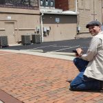 MJD kneeling with a camera in hand, smiling at the photographer taking is picture