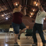 Rev. Avende in a crane pose with Rev. Dangler with arms wide, under a roof