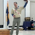 MJD in Scouting America uniform holding up a wooden arrow with leather pieces hanging off