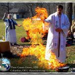 Rev Dangler stands beside a flame that has risen from a small firepit, in the shape of a person