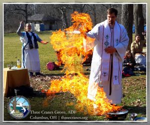 Rev Dangler stands beside a flame that has risen from a small firepit, in the shape of a person