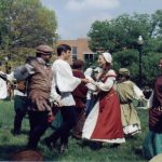 People in medieval garb dancing in a grassy area