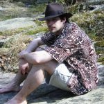 MJD in a Hawaiian shirt sits on the bank of a river